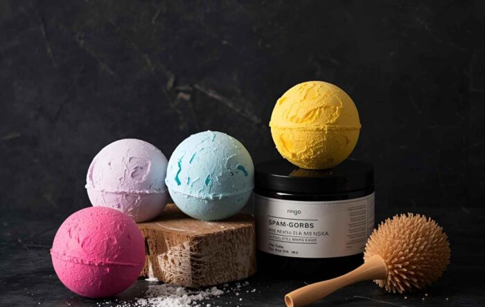 colorful bath bombs and spa products arranged on a dark background with a wooden massage brush