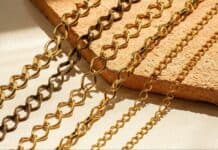 What Makes Gold Jewelry the Perfect Choice for Every Style? Golden chains of varying link styles rest on a textured surface, illuminated by warm sunlight, creating a luxurious and elegant atmosphere.