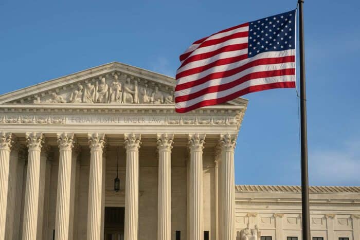 Supreme Court of the United States with American flag, symbolizing ruling on presidential authority and executive oversight over federal regulators. ai image via axcessnews.