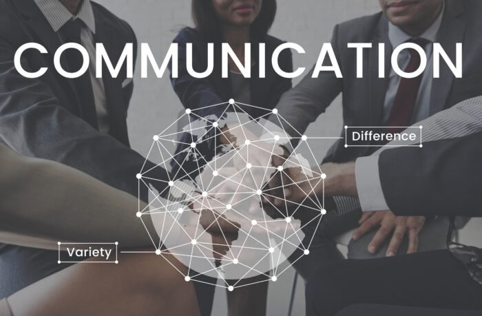 Business professionals in suits join hands overlaid with network lines. Words "Communication," "Variety," and "Difference" suggest teamwork.