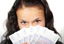 When the Math Makes Sense: Strategic Times to Utilize Short-Term Borrowing Young woman with dark hair playfully holds several British banknotes in front of her face, eyes visible above, conveying a sense of mystery and excitement.