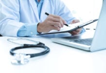 From Data to Dollars: How Clear Communication Drives Medical Product Sales A doctor in a white coat writes on a clipboard at a desk with a stethoscope and laptop, conveying a professional and focused atmosphere.