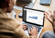 Designing for Growth: The Conversion Data You Need to Build a Better Website A person works at a laptop displaying an analytics dashboard with charts, gesturing as if discussing the data in a bright office setting.